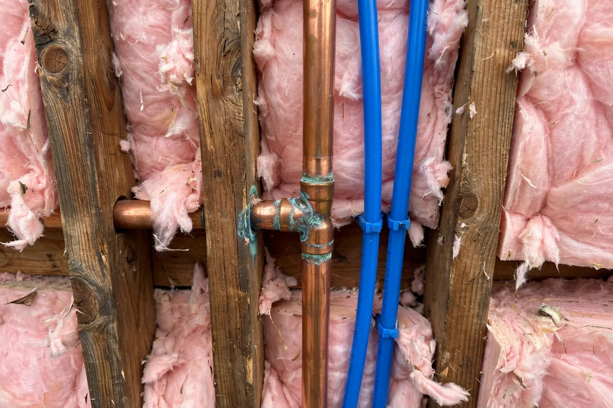 Copper and PEX water pipes inside an open wall cavity